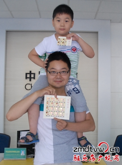 圖為6月13日,一對父子在市中心郵政所展示“感恩父親”特種郵票 .JPG